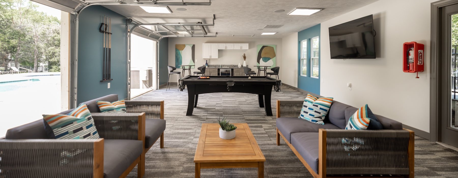 a clubroom with couches, a pool table and a tv
