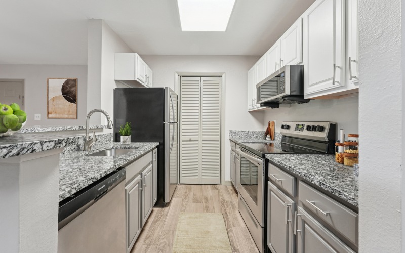 Kitchen with granite countertops, white cabinetry and stainless steel appliances